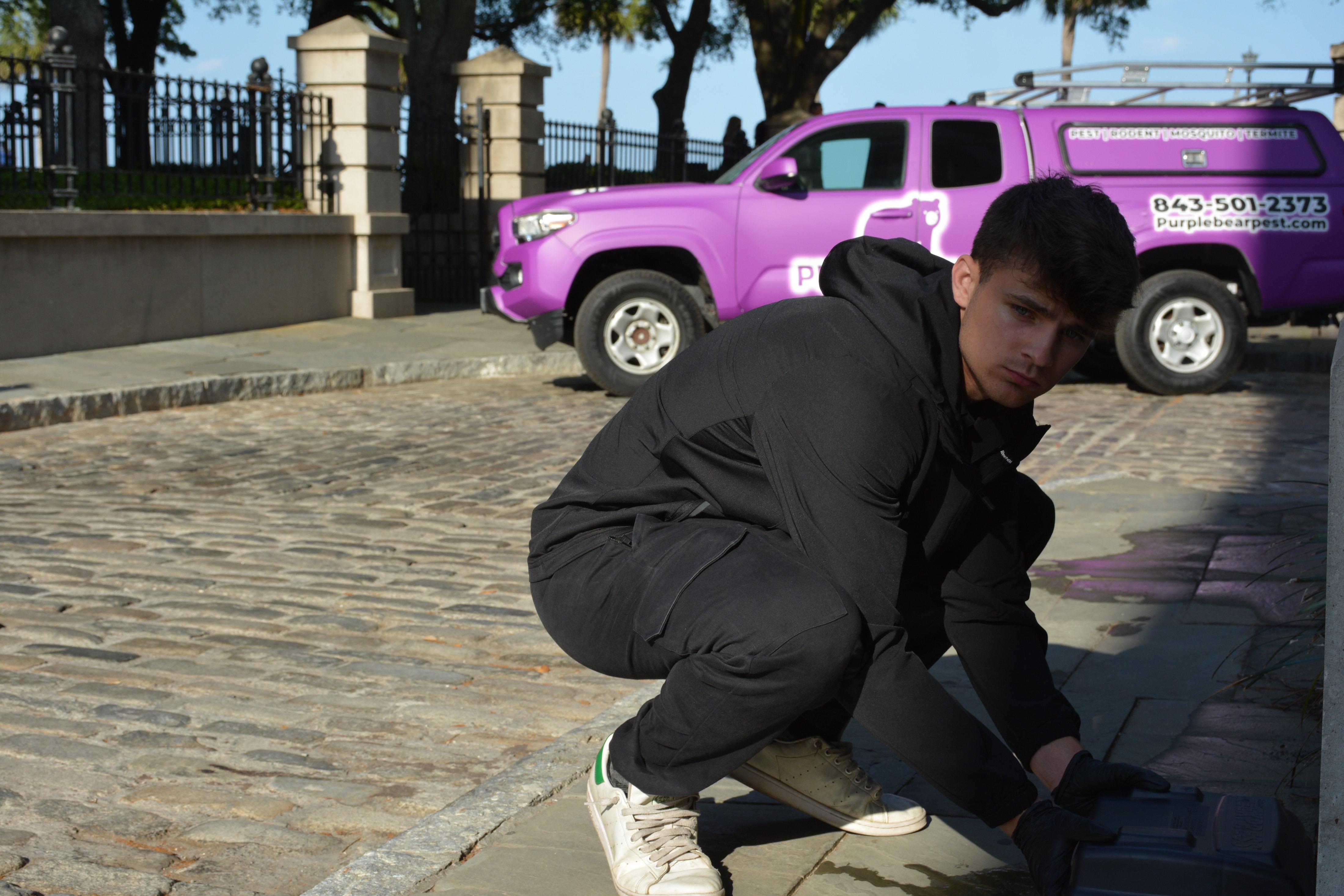 Caiden Hill, founder of Purple Bear Pest Control, with the branded purple truck in Charleston SC